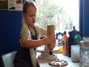 Little girl using paints at Piggery Pottery Cwm y Glo North Wales