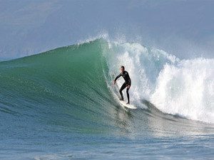 A surfer surfing big wave at Porth Neigwl Hells Mouth beach Llyn Peninsula North Wales