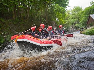 Paddling in an inflatable down rapids at the National White Water Rafting Centre Bala