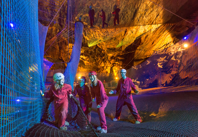 Family enjoying jumping net to net underground at Bounce Below Zip World Caverns