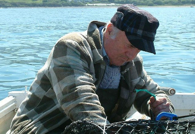 Image of a fisherman checking his lobster pots off Trefor Beach