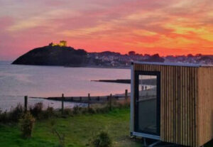 A sunset view of Criccieth sauna with the sea and Criccieth castle in the background
